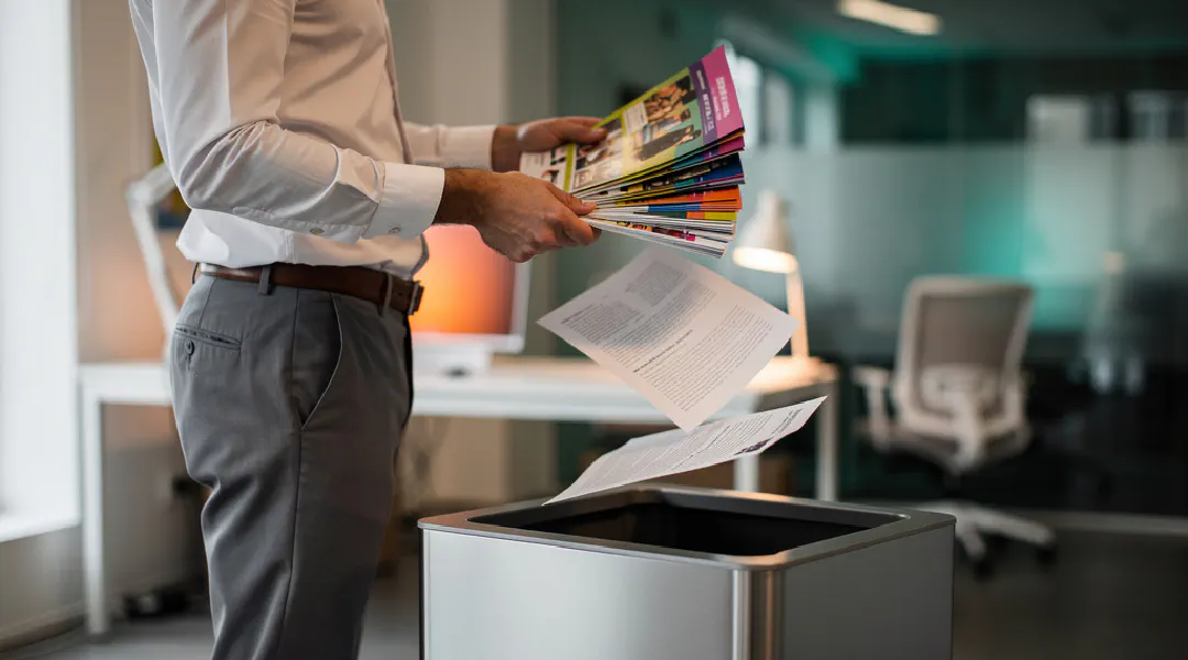 Iemand sorteert folders: een paar bewaren, de rest bij het oud papier
